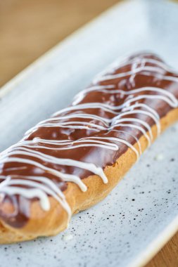 Çikolata ile geleneksel Fransız eclairs. Üzerine çikolata kreması ile süslenmiş kek ahşap bir masanın üzerinde