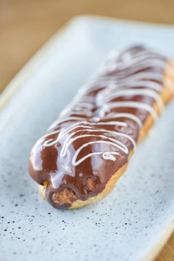 Çikolata ile geleneksel Fransız eclairs. Üzerine çikolata kreması ile süslenmiş kek ahşap bir masanın üzerinde