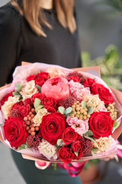 Kırmızı tonlar Kadınların elinde güzel bir buket karışık çiçek. Çiçekçi dükkanındaki çiçekçinin işi. Güzel, taze bir buket. Çiçek teslimatı