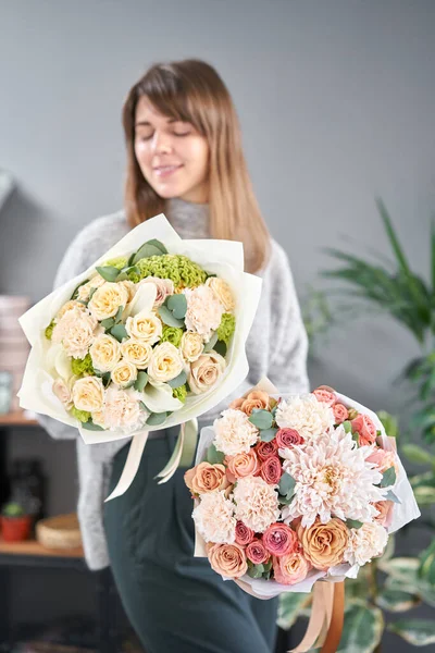 Dos hermosos ramos de flores mixtas en manos de mujeres. el trabajo de la floristería en una florería. Flor fresca cortada . — Foto de Stock