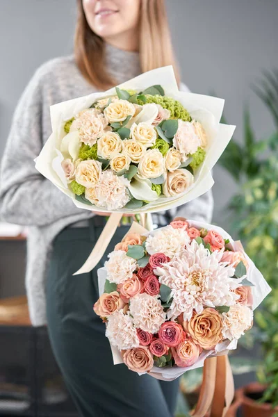 Dois belos buquês de flores mistas em mãos de mulheres. o trabalho da florista em uma loja de flores. Flores frescas cortadas . — Fotografia de Stock