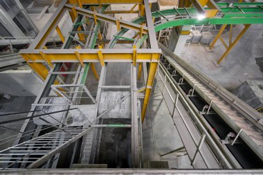 Karıştırıcıdaki malzemelerin taşıyıcı bandı. House-Building fabrikasının atölyesinde çalışanlar. Endüstriyel iç mekan. Beton fabrikası.