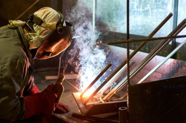 Kaynakçı kaynak makinesinde çalışıyor. Parlak ışıklar ve duman demir kaynaklama ve ağları güçlendirme. Beton takviyesi için. Ev inşa fabrikası. Endüstriyel iç mekan. Beton fabrikası.