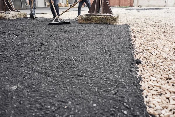 Colocando asfalto nuevo, cubriendo la fosa, sobre los escombros. Los trabajadores llevan palas y usan laúd de asfalto para asfalto suave y caliente . — Foto de Stock