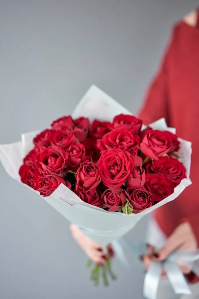 Buquê mono vermelho de rosas Bush em mãos de mulheres. Loja floral europeia. o trabalho da florista em uma loja de flores. Entrega flor de corte fresco . — Fotografia de Stock