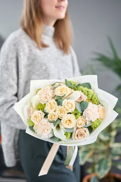 Tienda floral europea. Hermoso ramo de flores mixtas en manos de mujeres. el trabajo de la floristería en una florería. Entrega flor fresca cortada . — Foto de Stock