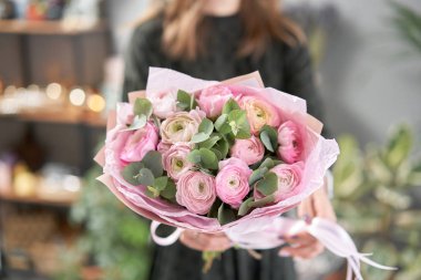 Kadınların elinde İranlı düğün çiçeği. Yeşil okaliptüslü soluk pembe ranunculus çiçekleri. Çiçekçi dükkanındaki çiçekçinin işi.