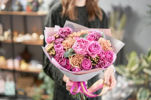 Peonías rosadas, Sarah Bernhardt y diferentes flores. Tienda floral europea. Hermoso ramo en manos de mujeres. el trabajo de la floristería en una florería. Entrega flor fresca cortada . — Foto de Stock