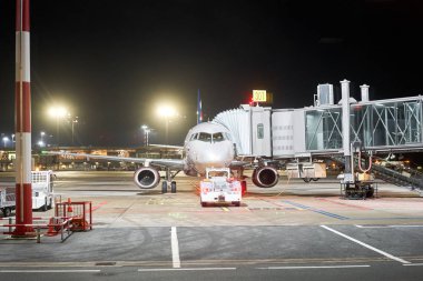 Riga, Letonya - 11 Aralık 2019. Riga Uluslararası Havaalanı, Rix. Modern beyaz yolcu uçağı gece park yerinde duruyor ve uluslararası havaalanından yolcu almaya hazırlanıyor..