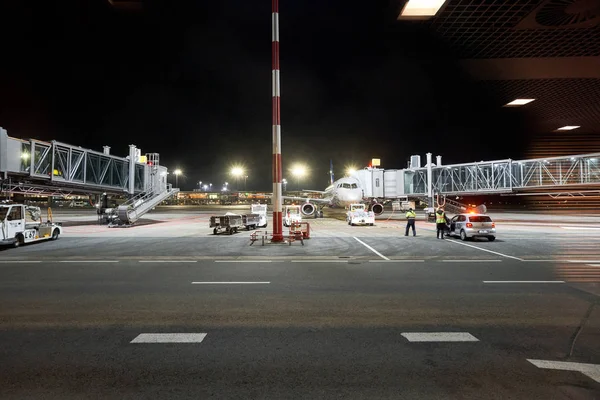 Рига, Латвия - 11 декабря 2019 года. Рижский международный аэропорт, RIX. Авиационный маршал встречает пассажирский самолет в аэропорту при ночном обзоре. Самолет взлетает на стоянку . — стоковое фото