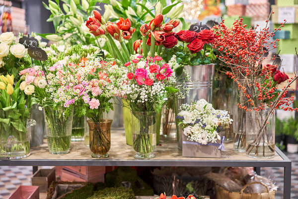 Вазы с разноцветными цветами, витрина цветочного магазина. Прекрасные весенние букеты. - Да. Маленький семейный бизнес. Рабочий флорист. копировальное пространство