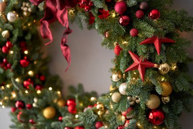 Gri duvarda taze ladin çelengi. Kırmızı, altın süslemeli ve taşaklı Xmas halkası. Noel havası.