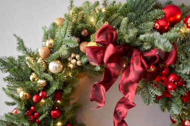 Gri duvarda taze ladin çelengi. Kırmızı, altın süslemeli ve taşaklı Xmas halkası. Noel havası.