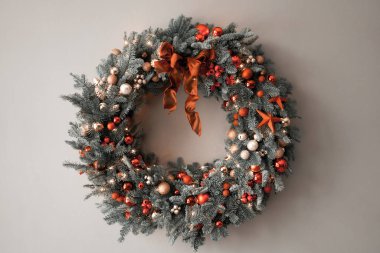 Gri duvarda taze ladin çelengi. Kırmızı, altın süslemeli ve taşaklı Xmas halkası. Noel havası.