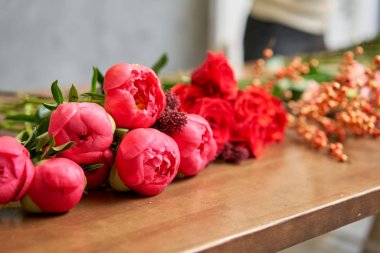 Adım adım çiçekçi kadın kırmızı güzel bir buket karışık çiçek yaratır. Yakışıklılar. Eğitim, yüksek lisans ve çiçekçilik dersleri. Çiçek teslimatı. Avrupa çiçekçi dükkânı konsepti.