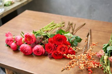 Adım adım çiçekçi kadın kırmızı güzel bir buket karışık çiçek yaratır. Yakışıklılar. Eğitim, yüksek lisans ve çiçekçilik dersleri. Çiçek teslimatı. Avrupa çiçekçi dükkânı konsepti.