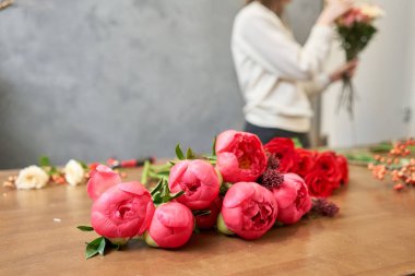 Adım adım çiçekçi kadın kırmızı güzel bir buket karışık çiçek yaratır. Yakışıklılar. Eğitim, yüksek lisans ve çiçekçilik dersleri. Çiçek teslimatı. Avrupa çiçekçi dükkânı konsepti.