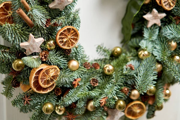 白いドアの上に新鮮なトウヒの美しいクリスマスの花輪の詳細を閉じます。家への入り口。クリスマス気分。クリスマスツリー. — ストック写真