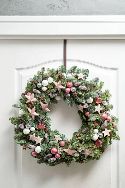 Piękny świąteczny wieniec ze świeżego świerku na białych drzwiach. Wejście do domu. Boże Narodzenie. Choinka. — Zdjęcie stockowe