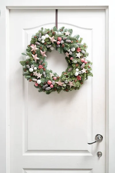 Frumoasă coroană de Crăciun de molid proaspăt pe ușa albă. Intrarea în casă. Starea de Crăciun. Arborele de Crăciun . — Fotografie, imagine de stoc