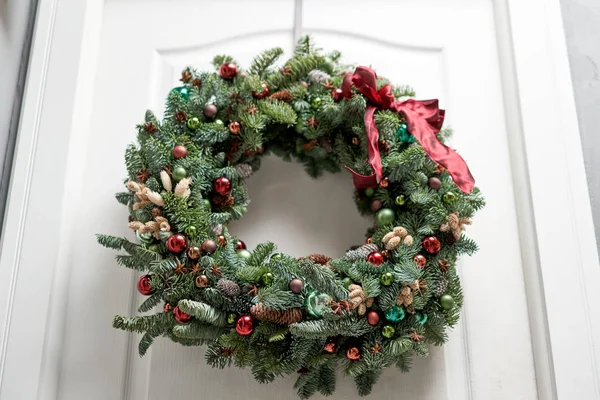 Hermosa corona de Navidad de abeto fresco en la puerta blanca. Entrada a la casa. Humor de Navidad. Árbol de Navidad . — Foto de Stock