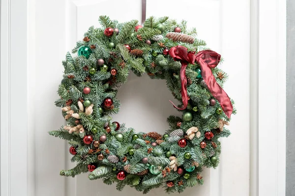 Bela coroa de Natal de abeto fresco na porta branca. Entrada para a casa. Humor de Natal. Árvore natal . — Fotografia de Stock