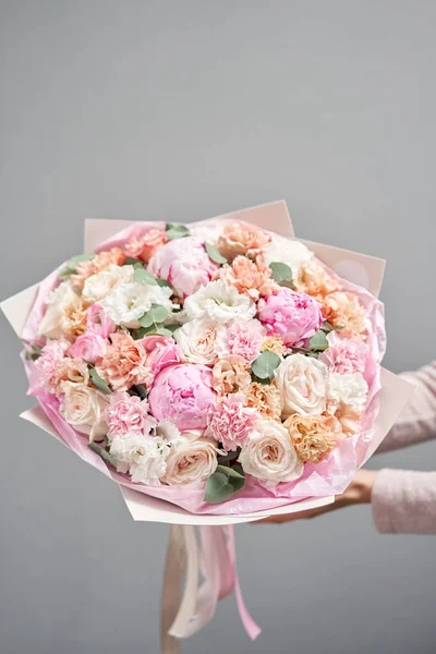 Peonías rosadas, Sarah Bernhardt y diferentes flores. Tienda floral europea. Hermoso ramo en manos de mujeres. el trabajo de la floristería en una florería. Entrega flor fresca cortada . — Foto de Stock