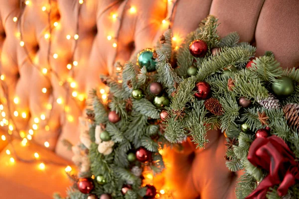 Κοντινό πλάνο Όμορφο γιορτινό στεφάνι από φρέσκο έλατο στον καναπέ. Χριστουγεννιάτικη διάθεση. Χριστουγεννιάτικο δέντρο. Bokeh του Garland φώτα στο παρασκήνιο — Φωτογραφία Αρχείου