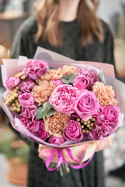 Pedónias cor-de-rosa, Sarah Bernhardt e flores diferentes. Loja floral europeia. Belo buquê em mãos de mulheres. o trabalho da florista em uma loja de flores. Entrega flor de corte fresco . — Fotografia de Stock