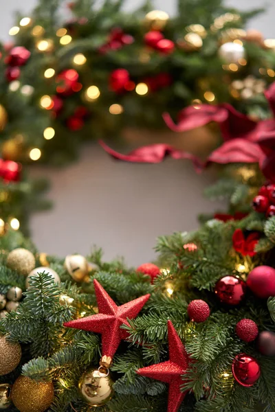 Schöner festlicher Kranz aus frischer Fichte an grauer Wand. Weihnachtskreis mit roten und goldenen Ornamenten und Kugeln. Weihnachtsstimmung. — Stockfoto