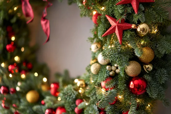 Bela grinalda festiva de abeto fresco na parede Cinza. Xmas circlet com ornamentos vermelhos e dourados e bolas. Humor de Natal . — Fotografia de Stock