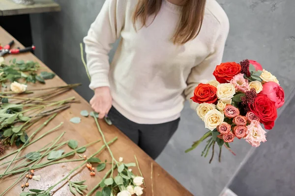 Concepto europeo de tienda floral. Florista mujer crea rojo hermoso ramo de flores mixtas. Hermoso grupo fresco. Cursos de educación, master class y floristería. Entrega de flores . — Foto de Stock