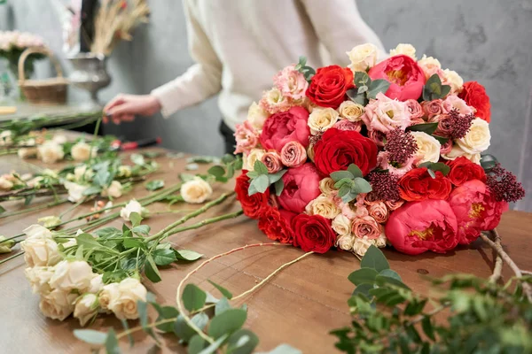 Concepto europeo de tienda floral. Florista mujer crea rojo hermoso ramo de flores mixtas. Hermoso grupo fresco. Cursos de educación, master class y floristería. Entrega de flores . — Foto de Stock