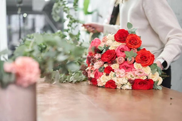 Concepto europeo de tienda floral. Florista mujer crea rojo hermoso ramo de flores mixtas. Hermoso grupo fresco. Cursos de educación, master class y floristería. Entrega de flores . — Foto de Stock