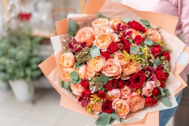 Kırmızı tonlar Kadınların elinde güzel bir buket karışık çiçek. Çiçekçi dükkanındaki çiçekçinin işi. Güzel, taze bir buket. Çiçek teslimatı