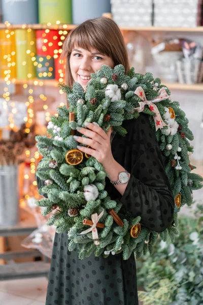 Bela grinalda festiva de abeto fresco em mãos de mulher. Humor de Natal. Bokeh de luzes de guirlanda no fundo . — Fotografia de Stock