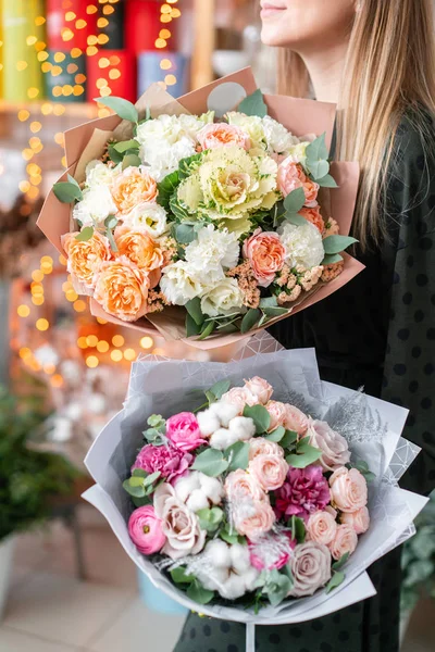 Європейський квітковий магазин. Два прекрасних букети мішаних квітів у руках жінок. Робота квіткаря у квіткарні. Свіжа зрізана квітка.. — стокове фото