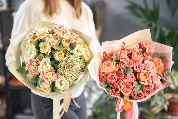 Europese bloemenwinkel. Twee prachtige boeketten van gemengde bloemen in de handen van vrouwen. het werk van de bloemist in een bloemenwinkel. Levering verse snijbloem. — Stockfoto