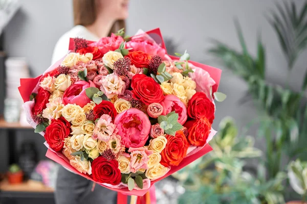 Tons vermelhos Belo buquê de flores mistas em mãos de mulheres. o trabalho da florista em uma loja de flores. Bonito buquê fresco. Entrega de flores — Fotografia de Stock