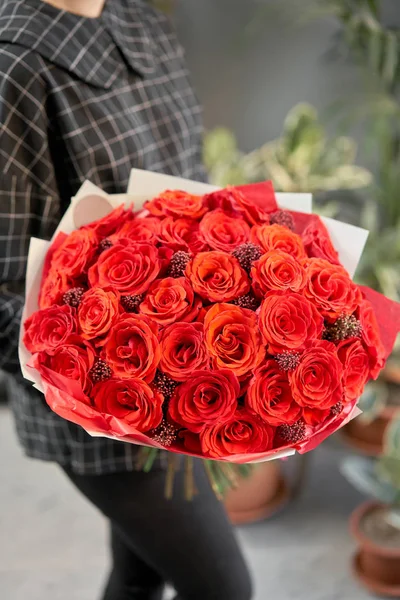 Buquê mono de rosas vermelhas em mãos de mulheres. Loja floral europeia. o trabalho da florista em uma loja de flores. Entrega flor de corte fresco . — Fotografia de Stock