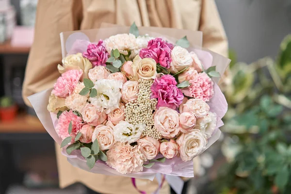 Tienda floral moderna. Trabajo terminado de la floristería. Lindo ramo de flores mixtas en manos de mujeres. Entrega flor fresca cortada . — Foto de Stock