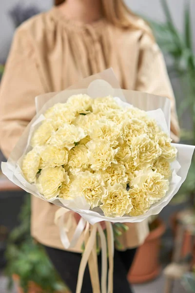 Lemon color mono bouquet of carnation in womans hands. European floral shop. the work of the florist at a flower shop. Delivery fresh cut flower.