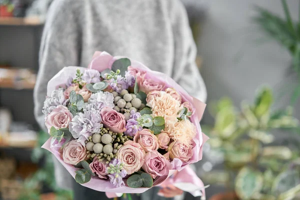 Tienda floral moderna. Trabajo terminado de la floristería. Lindo ramo de flores mixtas en manos de mujeres. Entrega flor fresca cortada . — Foto de Stock