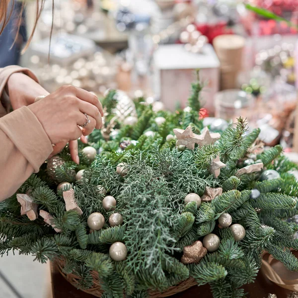 Uma mulher decora um arranjo de Natal. Master class em fazer ornamentos decorativos. Decoração de Natal com suas próprias mãos. A celebração do ano novo. Loja de flores — Fotografia de Stock