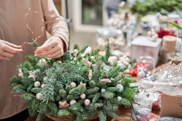 Una mujer decora un arreglo navideño. Clase magistral sobre la fabricación de ornamentos decorativos. Decoración de Navidad con sus propias manos. La celebración del año nuevo. Floristería — Foto de Stock