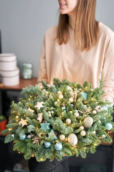 Piccola disposizione di abete fresco in un cesto di vimini. L'umore natalizio. Bellissimo bouquet nelle mani delle donne .. — Foto Stock