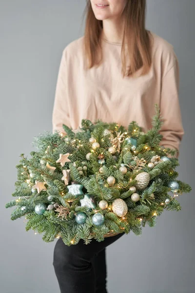 Piccola disposizione di abete fresco in un cesto di vimini. L'umore natalizio. Bellissimo bouquet nelle mani delle donne .. — Foto Stock