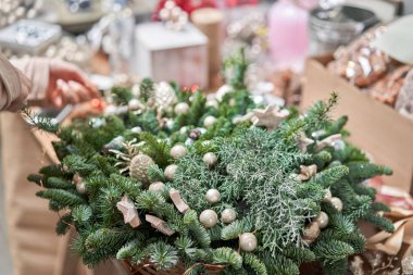 Bir kadın Noel düzenini süslüyor. Dekoratif süsler konusunda yüksek lisans. Noel dekorunu kendi elleriyle yaptılar. Yeni yıl kutlaması. Çiçekçi