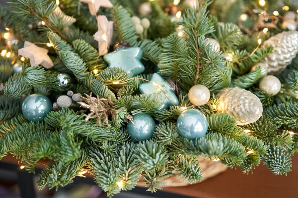 Grande arranjo de abeto fresco em uma cesta de vime. Decorado com bolas azuis, cones e pequenas estrelas. Humor de Natal. lâmpadas Garlands — Fotografia de Stock