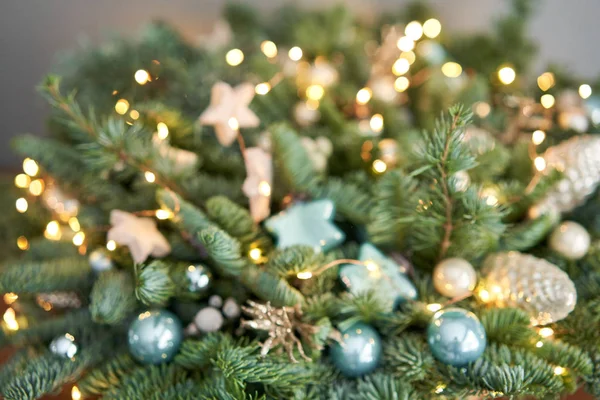 Desfoque abstrato. Grande arranjo de abeto fresco em uma cesta de vime. Decorado com bolas azuis, cones e pequenas estrelas. Humor de Natal. lâmpadas Garlands — Fotografia de Stock